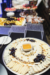 Large dish with different kinds of cheese, grape and sauce
