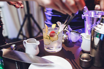 Cocktail with cucumber, raspberry and ice stands on the table