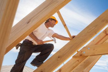 roofer builder working on roog structure of building on construction site