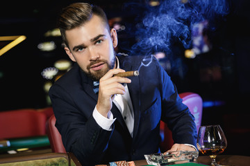 Rich handsome man smoking cigar in the casino