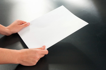 Female hands with paper on a black background. studio isolate.