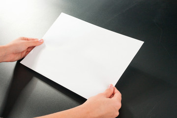 Female hands with paper on a black background. studio isolate.