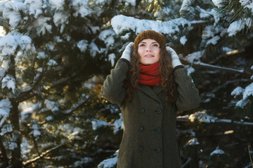 Pretty young woman in hat and coat play in snow winter park