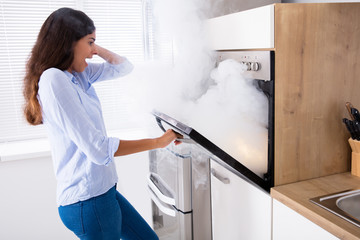 Shocked Woman Looking At Smoke Coming From Oven