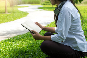 young asian girl sit on grass read a book in the garden