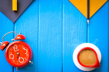 Good morning word,Retro Clock with cup and stationery of coffee on blue background,empty space