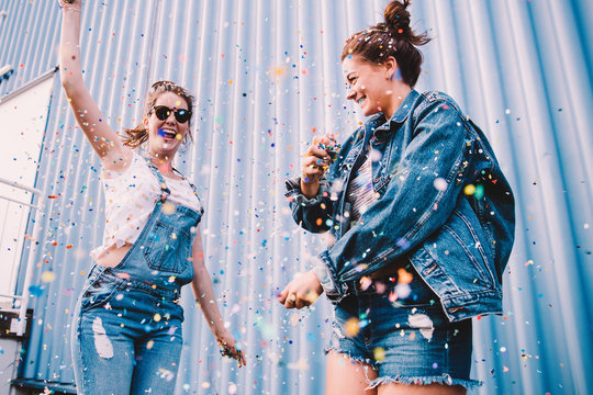 Young adult best friends cheering with confetti on party