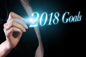 Hand holding a pen and writing 2018 goals
