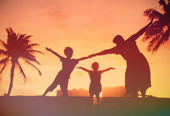 silhouette of family with kids play at sunset beach