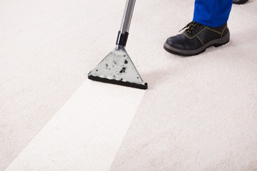Person Using Vacuum Cleaner For Cleaning Carpet