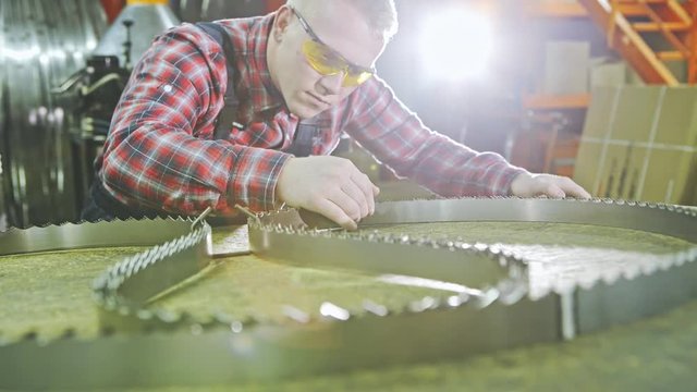 Man inspecting bandsaw teeth