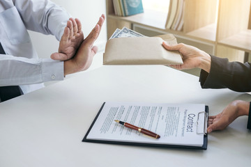 Bribery and corruption concept, Businessman refusing receive money in the envelope to agreement...