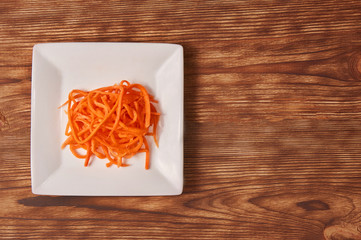 Grated carrots in a white cup isolated on a wooden background. Isolate. Food background.