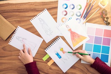 Close up of professional Fashion designer working and drawing sketches for clothes in workplace and color charts
