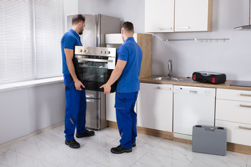Two Men Fixing Oven In Kitchen
