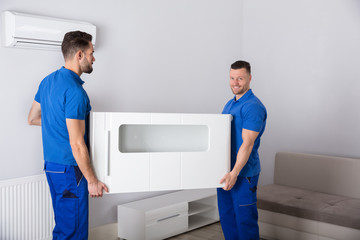 Two Movers Holding Furniture In Living Room