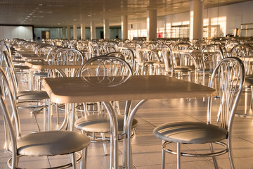 Metal chairs with high backs and tables in the morning sun in the cafe