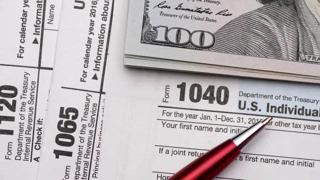 Tax Form 1040, 1120, 1065 and dollar bills, close up
