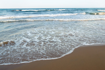 Sandy beach of the sea with an incoming foaming wave