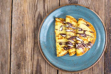 Pancakes stuffed with chocolate sauce, for breakfast on wooden table
