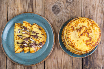 Pancakes stuffed with chocolate sauce, for breakfast on wooden table