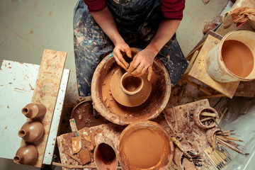 Potter at work. Workshop. Hands of a potter, creating an earthen jar on the circle