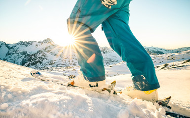 Legs of professional skier at sunset on relax moment in french alps ski resort - Winter sport concept with adventure guy on mountain top ready to ride down - Side view point with azure vintage filter - obrazy, fototapety, plakaty