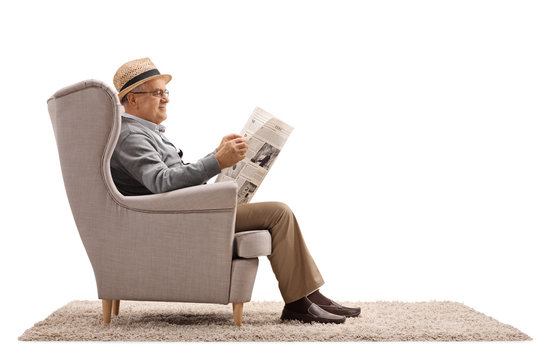 Mature man sitting in an armchair and reading a newspaper