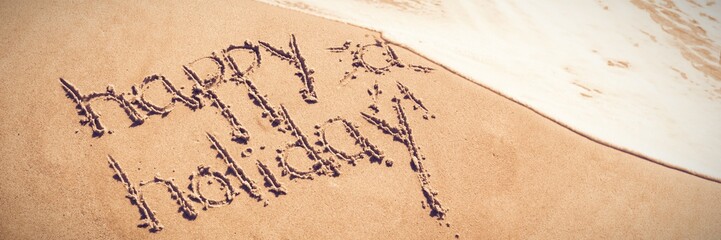 Happy holiday written text on sand