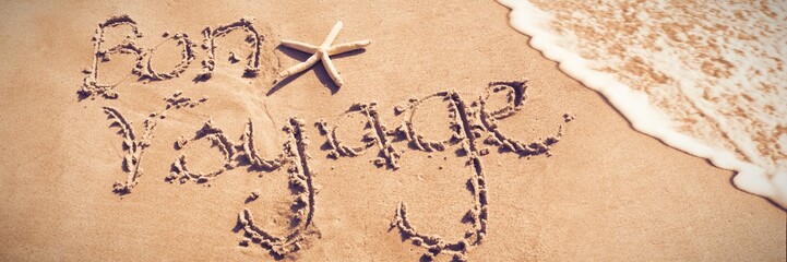 Bon voyage written on sand