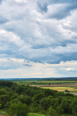 Obraz premium View from the hill to the green valley in cloudy weather.