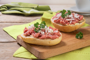 Buns with minced pork sausage, german mettwurst with onions and parsley garnish on a breakfast...