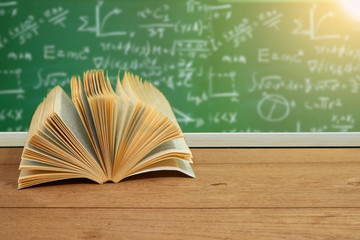 Text book on desk with green board background