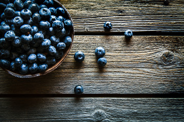Fresh blueberries in the bowl on a wooden table. Top view. Fruits, food