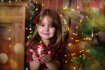 The girl holds a Christmas ball in hand