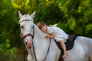 the little girl lies on a horse - obrazy, fototapety, plakaty