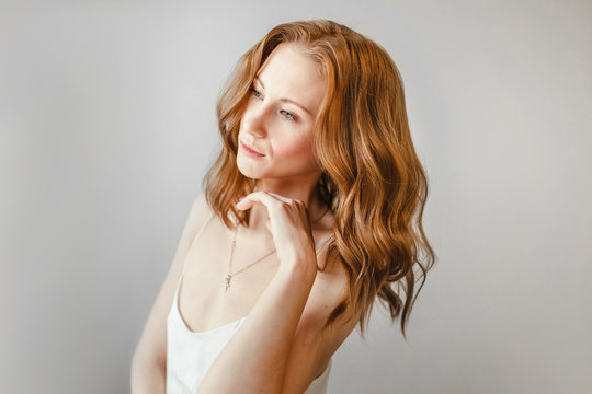 Ginger woman with wavy volumetric hair styling at white background