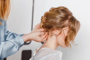 Fototapeta premium Closeup rear view hairdresser coiffeur makes hairstyle at beauty salon