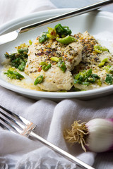 Hühnchenbrustfilet mit Frühlingszwiebeln und Parmesan auf einem Teller mit Besteck