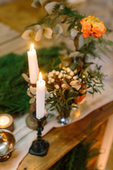 decoration, interior, romance concept. nearby with small but charming posies composed of small flowers, rose and various leaves there are few tall candles in different holders of wood and metal