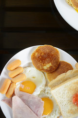 Breakfast includes fried egg, ham sausage pancakes eatimg nutritious every morning