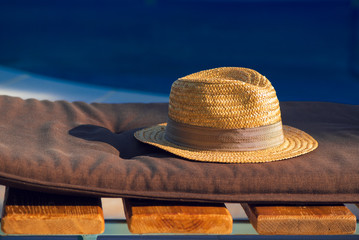 Straw hat on deck chair by the swimming pool