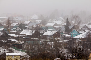 wooden houses huddle on the hillside in a foggy day