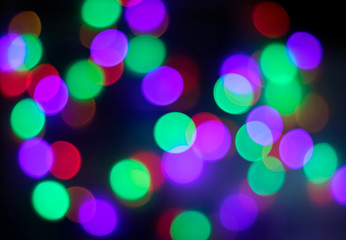 Colorful bokeh background made by light bulbs. In dark shadow.