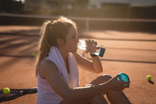 Tennis player drinking water after workout