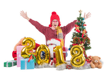 2018 Cheerful Boy with christmas and happy new year concept sittig among giftes, presents, dolls, christmas tree and xmas balloon, isolated on white background with clipping path