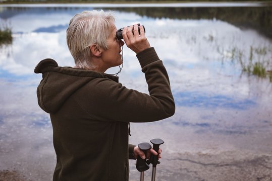 Senior woman hiker looking through binoculars