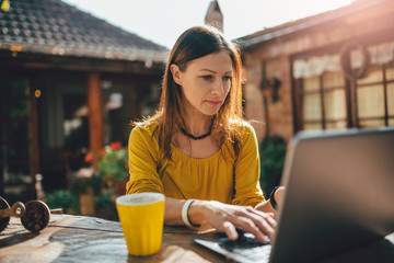 Women using laptop at backyard patio