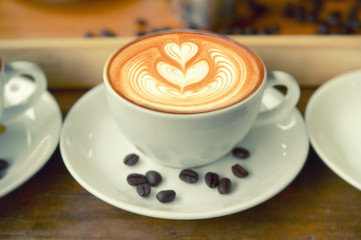 coffee cup latte art and coffee beans on old brown wooden
