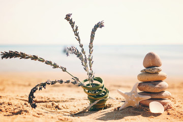 Pyramid of stones, a bunch of lavender and a starfish on the sand on the beach